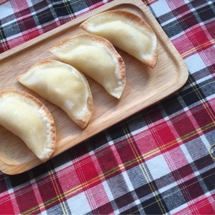 ギンガムチェックのテーブルクロスの上に木の四角い皿に盛られた餃子の皮で作った豆乳カスタードアップルパイ