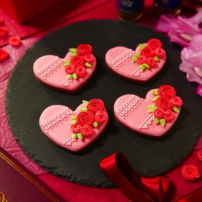 ピンクのアイシングとバラの砂糖菓子でデコレーションしたハート形のクッキー4枚