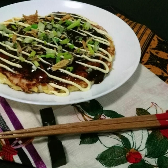箸置きに置かれた箸と、白い丸皿に盛られた米粉とお豆腐のお好み焼き 
