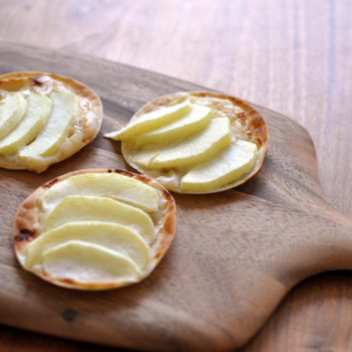 木のカッティングボードに置かれた餃子の皮で作ったオープンアップルパイ