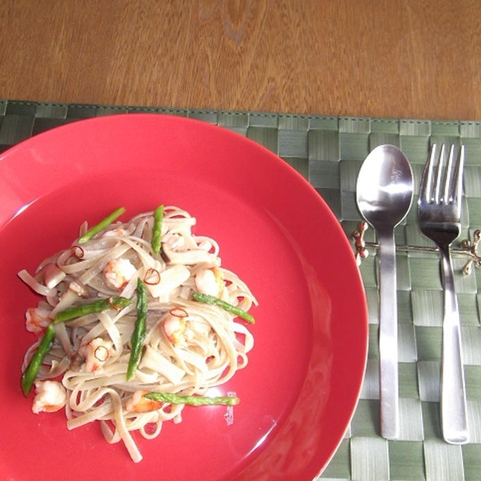 赤い皿に盛られたえびとアスパラとエリンギのパスタ