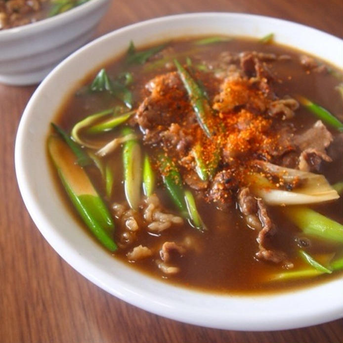 白い深皿に盛りつけられた牛肉と九条ねぎ入りのカレーうどん