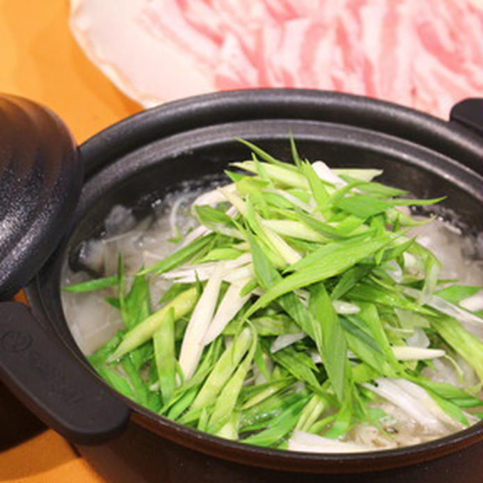 濃色の土鍋に入っている葉にんにくと桜島大根の豚しゃぶ鍋