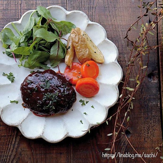 白い皿にのった、赤ワインのハンバーグソースがかかるハンバーグ、付け合わせの野菜