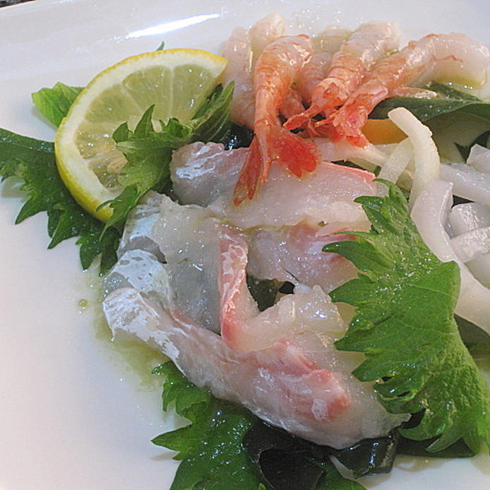 白い皿に盛りつけられた剣先イカと桜鯛、甘えびの刺身サラダ