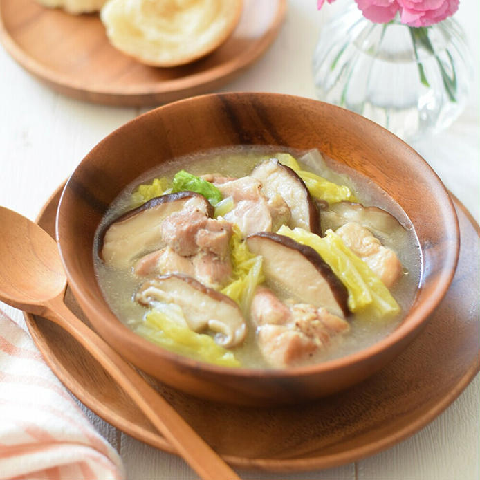 木の器に盛られた鶏肉と白菜としいたけのスープ