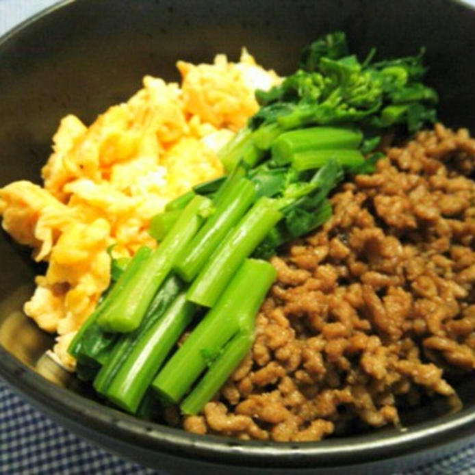 濃色の丼鉢に盛りつけられたかき菜と肉そぼろ、炒り卵の三色丼
