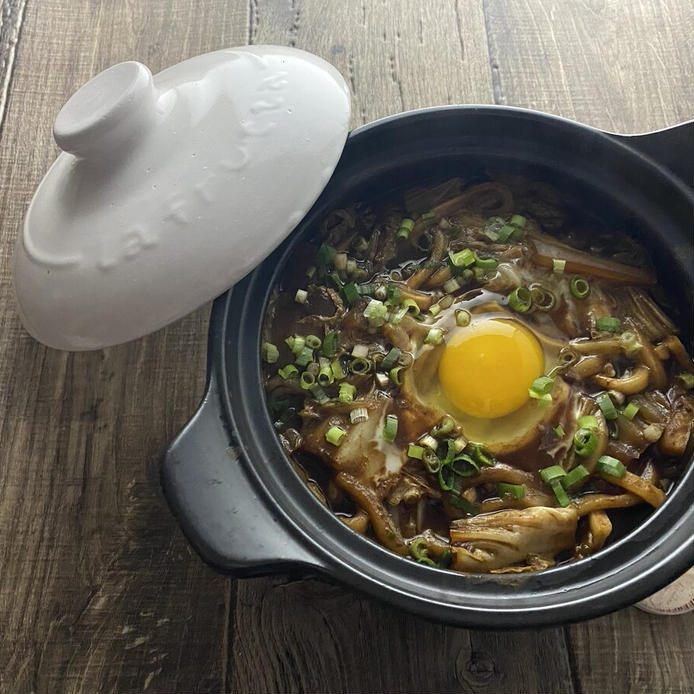 黒い土鍋に盛られた卵と白菜の味噌煮込みうどん