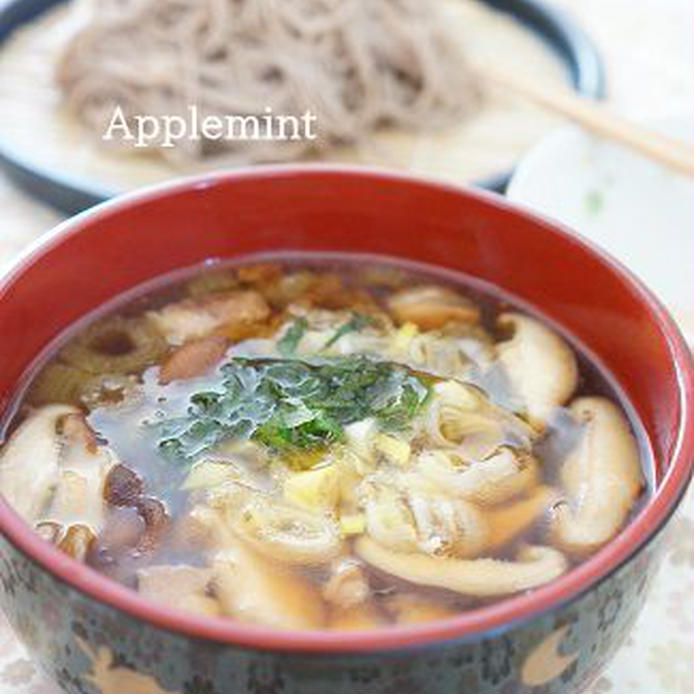 黒い容器に入った鶏肉と茸と大葉と長ネギとふきのつけ汁とそば