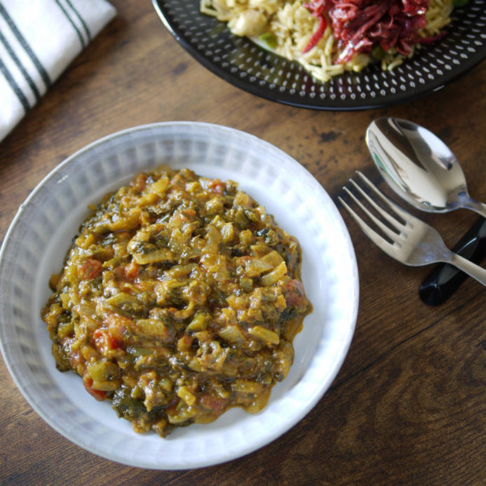 皿に盛りつけられたほうれん草や空心菜などの青菜入りサグカレー風