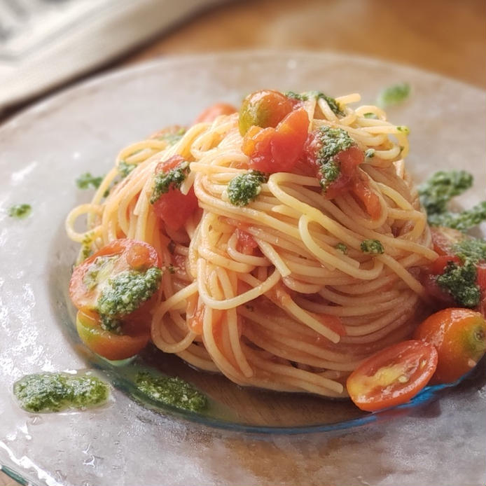 透明な皿に自家製バジルソースのトマトスパゲッティが盛り付けられている