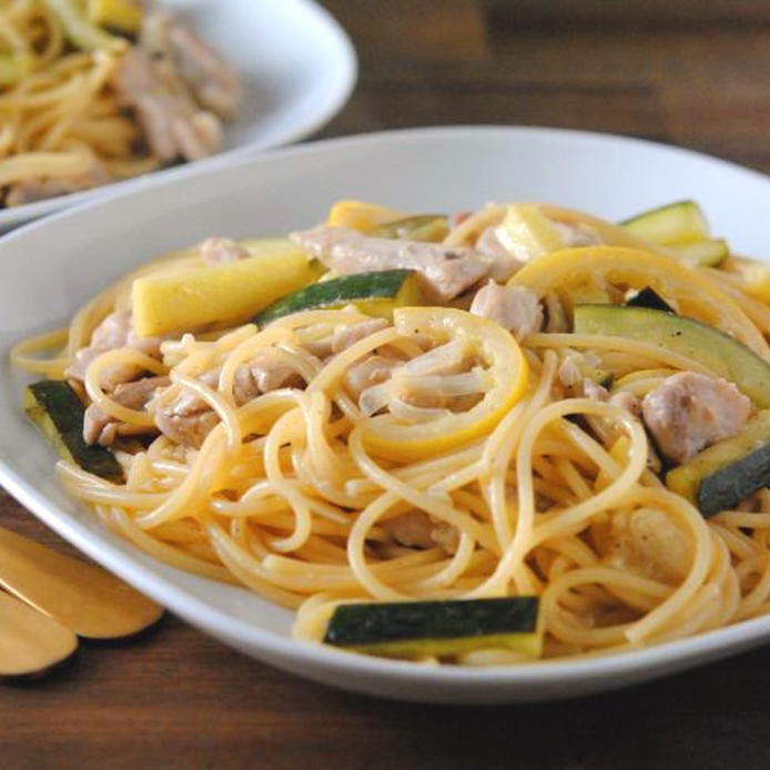 白色の角皿に盛られた鶏肉とレモンとズッキーニのパスタ