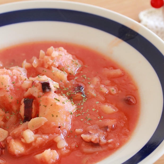 青い縁どりの皿に入った、たことじゃがいものトマト煮