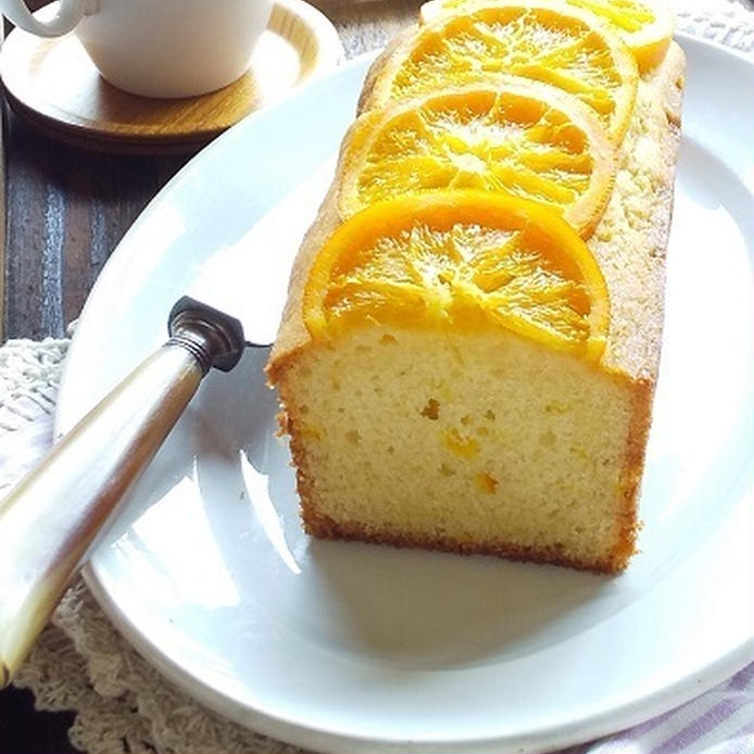 白い皿に盛りつけたオレンジパウンドケーキ、ケーキナイフ