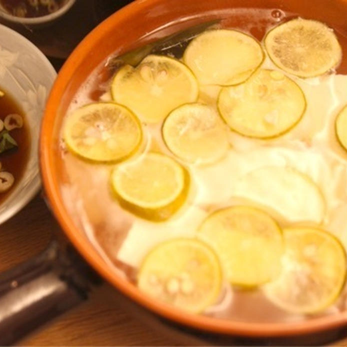 オレンジ色の土鍋に入っているすだち湯豆腐、小鉢のポン酢しょうゆ