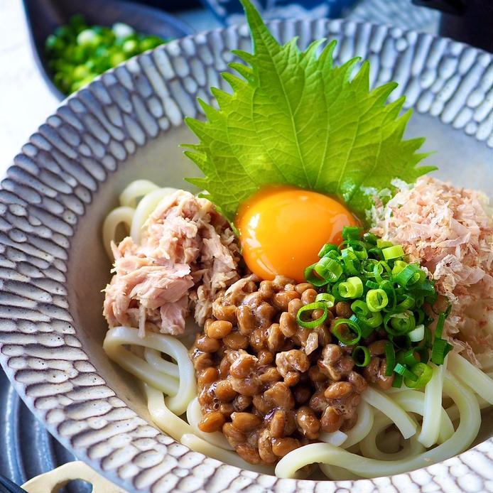 皿に盛りつけられたツナと納豆、おかか、卵黄のせぶっかけうどん