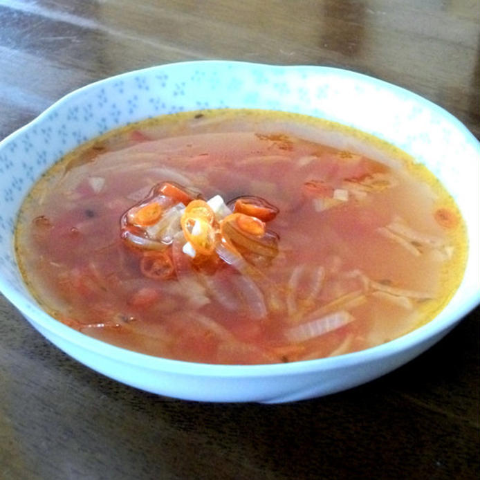 トマトや玉ねぎが浮いているスープを盛り付けた白い器