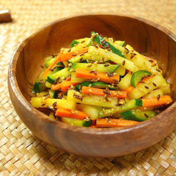 Adding homemade original curry powder as a seasoning to colorful   vegetable sticks quickly salad in a marinaded in some condiments