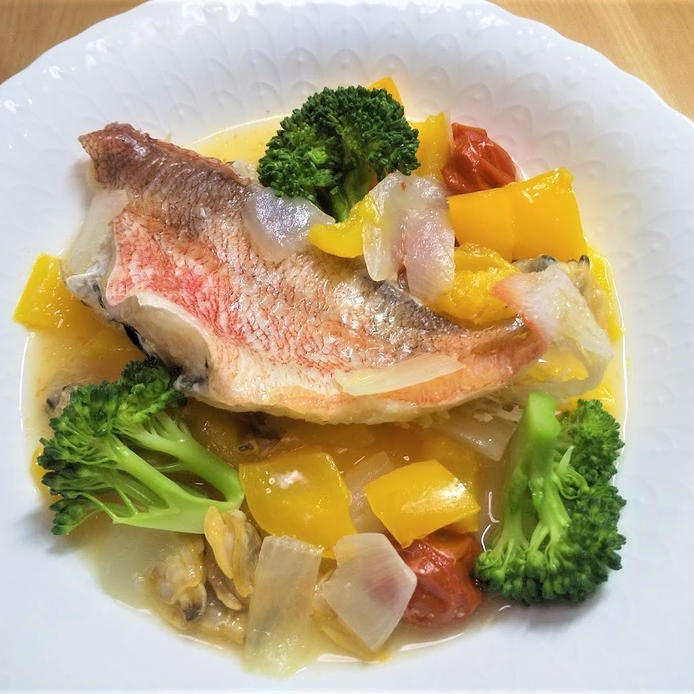 白い皿に盛りつけられた赤魚とあさり、野菜入りのアクアパッツァ