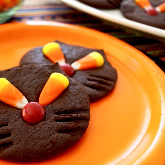 オレンジ色の皿に盛られた、黒猫クッキー2個