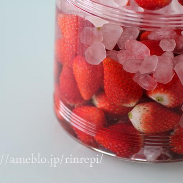 ガラス容器に入っている氷砂糖とヘタを取ったいちごの赤い実