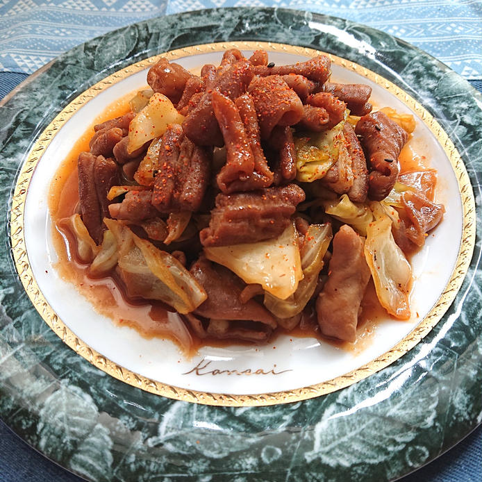 葉っぱの柄が書かれたお皿に、キャベツとホルモンのピリ辛炒めが盛られている