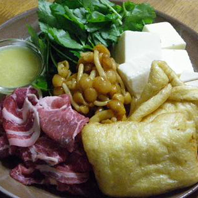 なめこ、豆腐、もち巾着、豚肩ロース肉、三つ葉がお皿に盛り付けられている