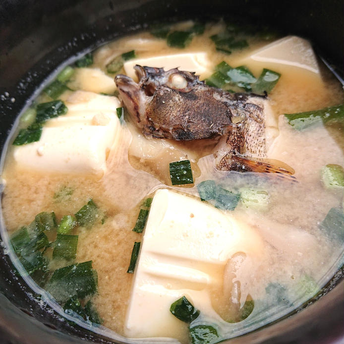 お椀に盛りつけられた頭つきのカサゴと豆腐、まいたけのみそ汁