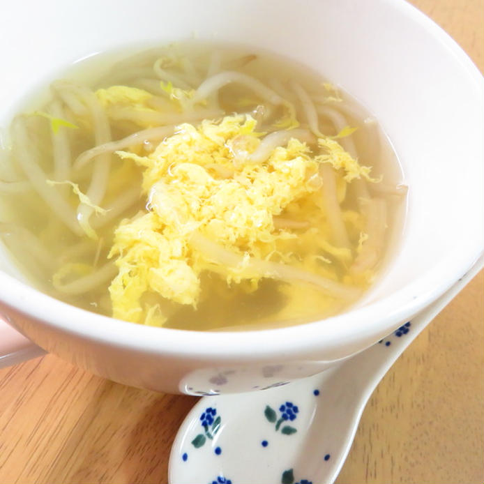 白いお椀に注がれたもやしと卵の生姜スープと添えられたレンゲ