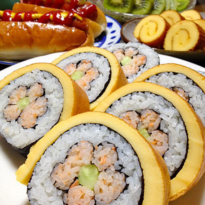 白い皿に並べられた伊達巻きの花巻き寿司