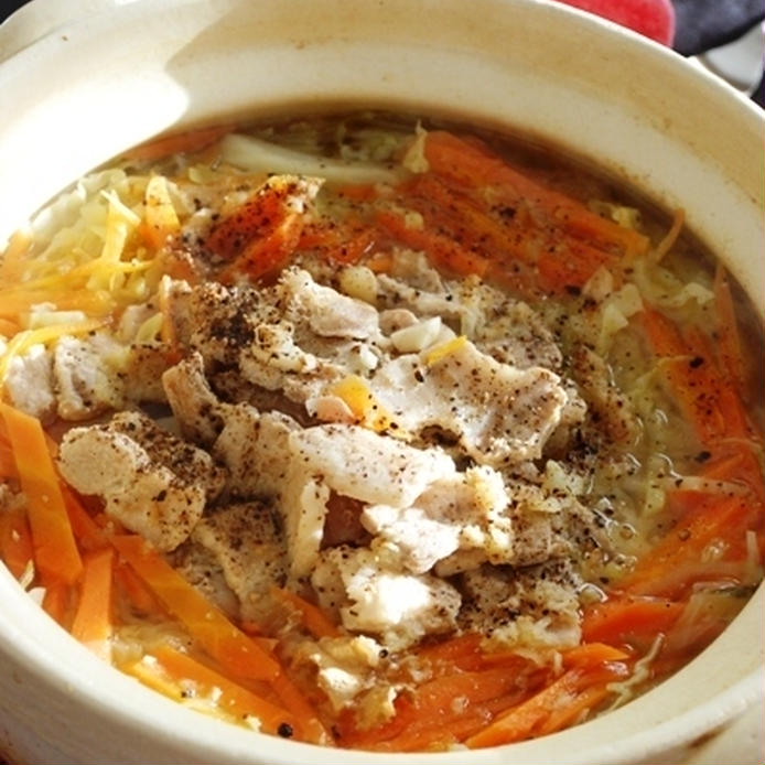 白い土鍋に入った豚バラ肉、キャベツ、ニンジンの黒胡椒スープ煮