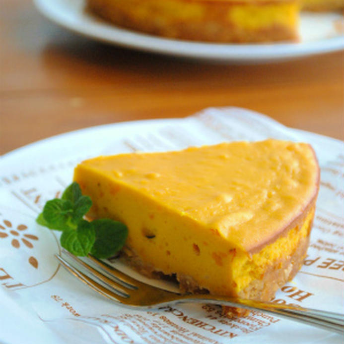 クッキングシートにオレンジ色のかぼちゃが入ったチーズケーキが一切れのっている様子