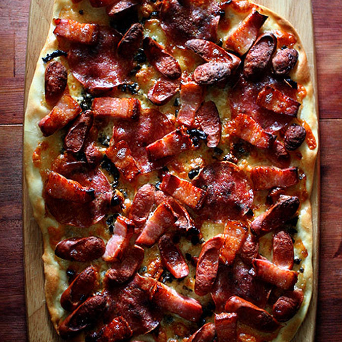 木製のお皿に盛られたサラミ・ベーコン・ソーセージのピザ